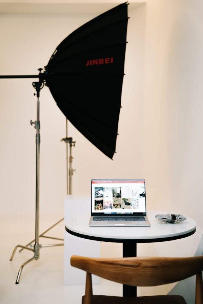 Studio setup featuring a softbox light and a laptop for photo editing, creating a clean and professional workspace.