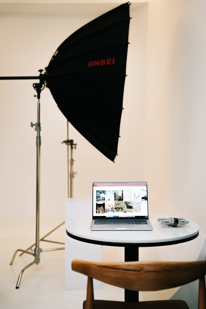 Studio setup featuring a softbox light and a laptop for photo editing, creating a clean and professional workspace.